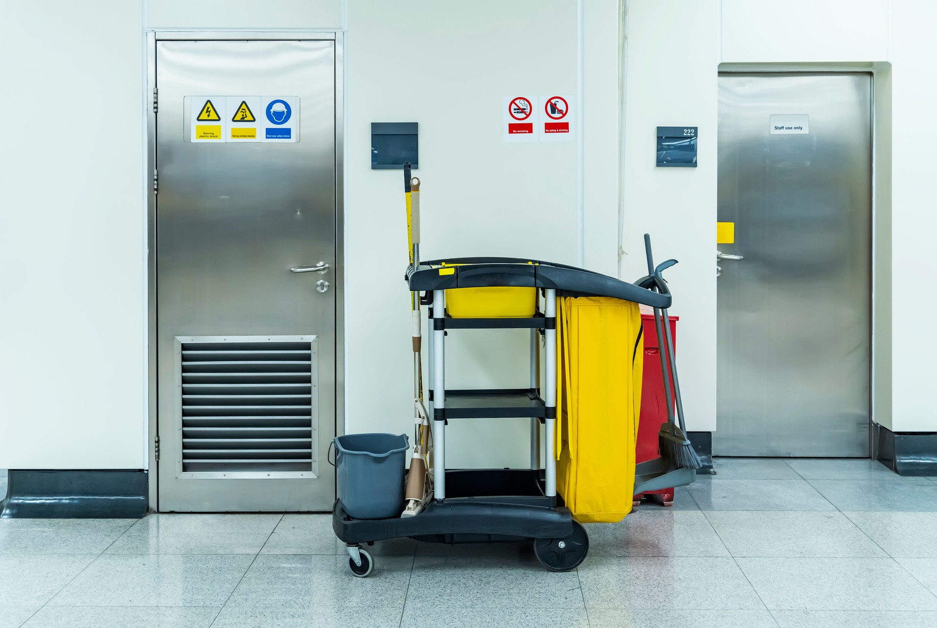 Cleaner cart in a public place with cleaning products: mop, buckets for cleaning the floor, broom scoop, household chemicals, household rags