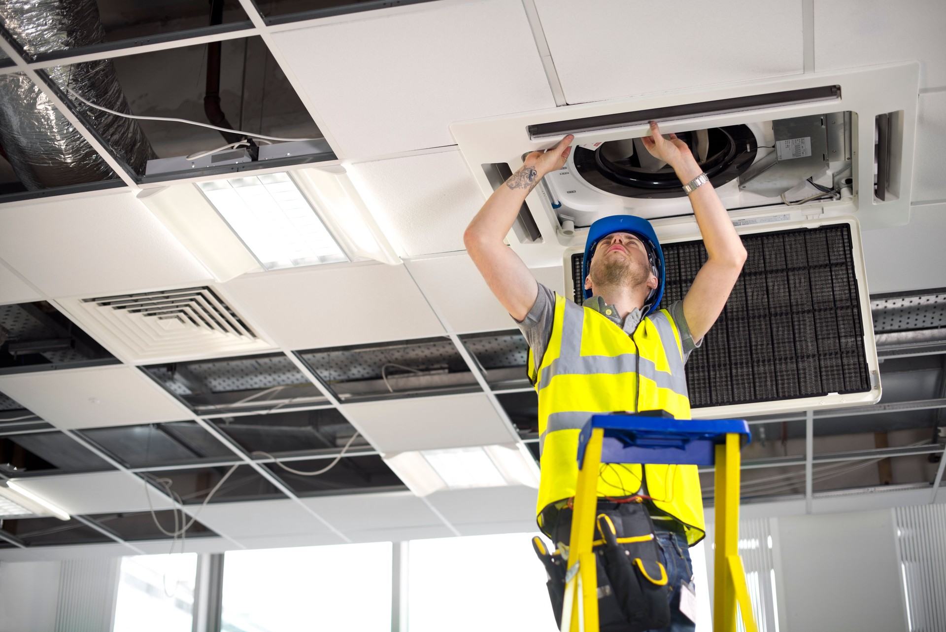 electrician fitting air conditioning to office interior